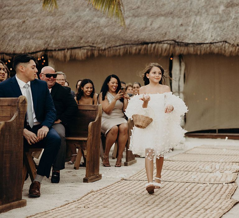 flower girl in a white strapless appliqué dress walking down the aisle at beach wedding 