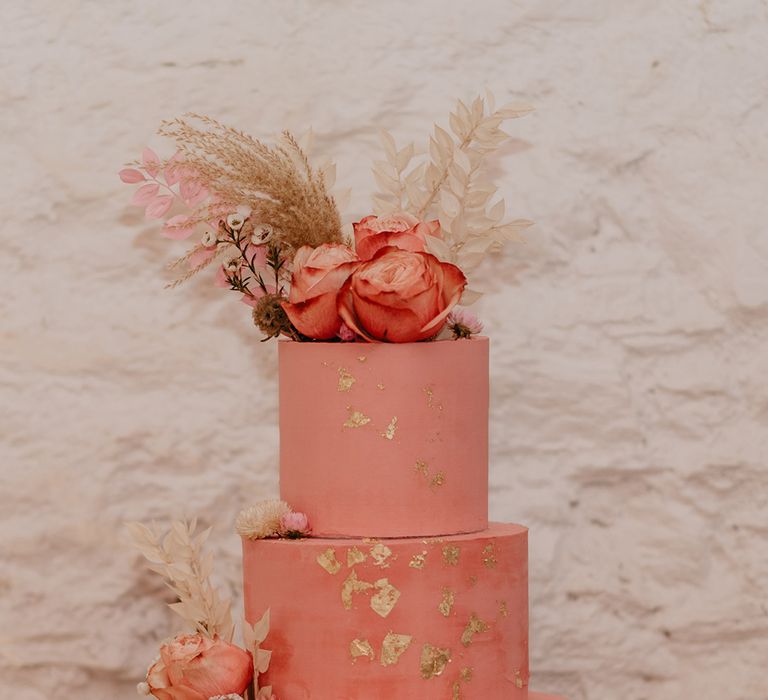 Pink wedding cake with gold flake icing and pampas grass cake topper decoration 