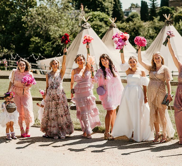 Bridal party wearing floral mismatched pink bridesmaid dresses 