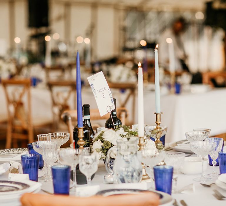 Dark blue, light blue, and white taper wedding candles with blue coloured glassware and china wedding plates 