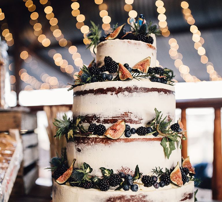 Naked wedding cake with blackberries, blueberries, and fig fruit decorations 