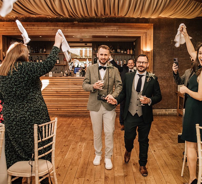 The wedding guests wave napkins to greet the grooms 