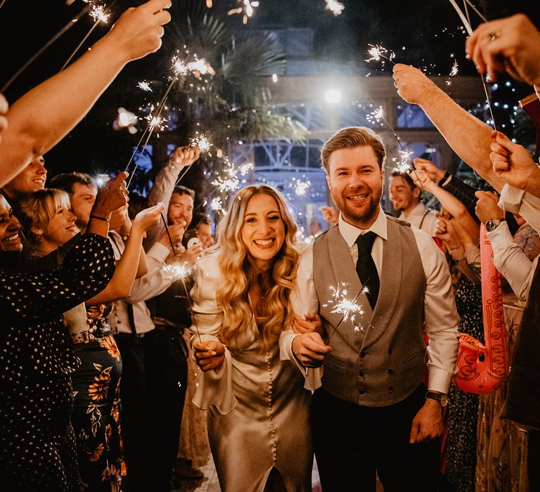 The bride and groom walk through a tunnel of sparklers after their country house wedding 