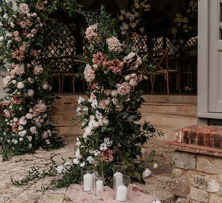 White and pink wedding flower columns with candles and pink drapery at outdoor ceremony 