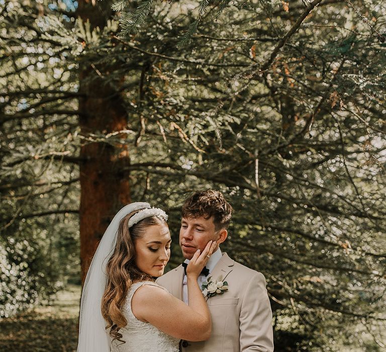 Groom in beige suit with black tie with bride in custom wedding dress and headband 