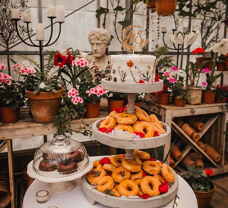 Tower stand with glazed doughnuts and a single tier wildflower decorated white iced wedding cake 