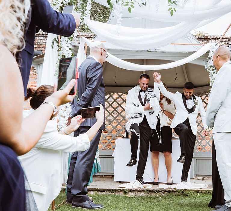 Two grooms break the glass at their wedding ceremony as part of Jewish custom 