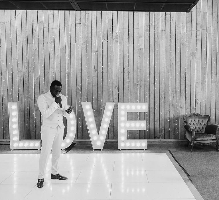 Groom in white wedding suit peforms wedding speech on the dancefloor 