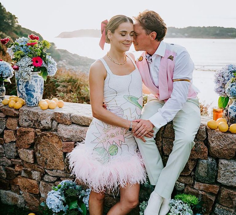 Bride in sequin wedding reception dress with feathers posing with the groom for their at home maximalist wedding 