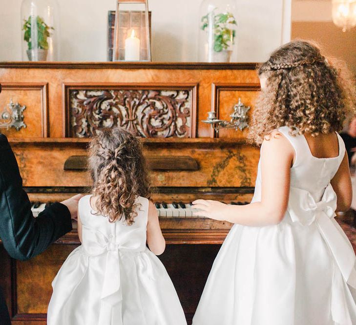 Flower girls with curly hair gathered around the piano 