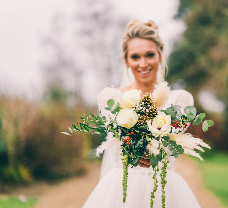 Winter wedding bouquet with white roses, pine cones and foliage 