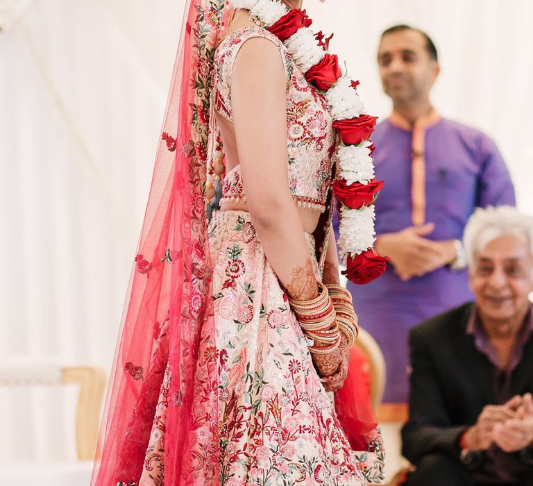 Indian bride in pink wedding dress with red veil at Hindu wedding ceremony 