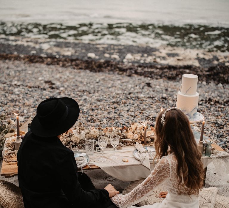 sweetheart table with wedding cake and grazing board on the beach 