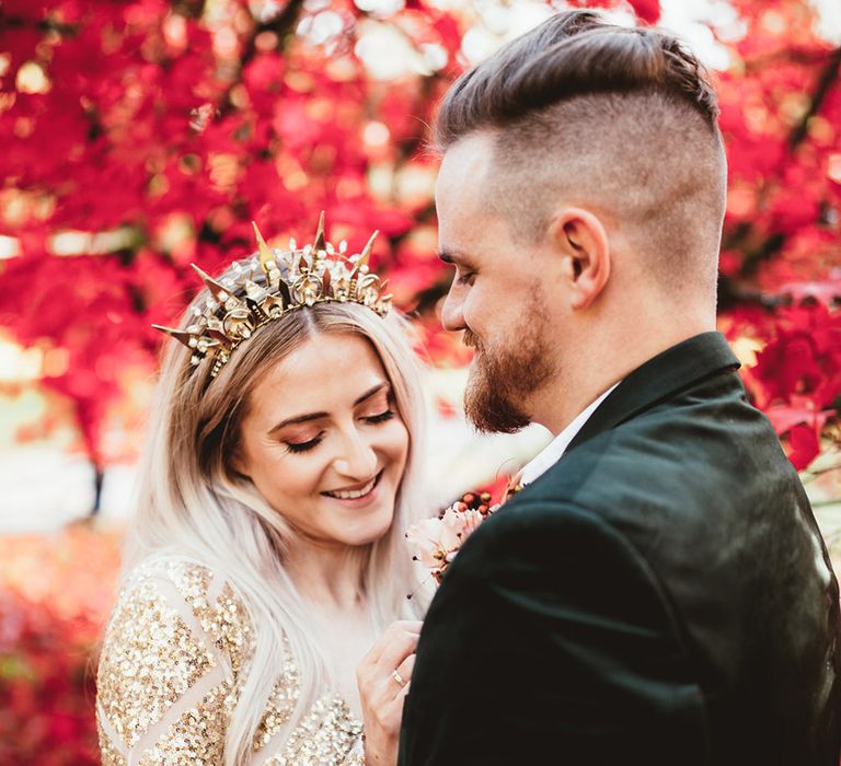 Bride laughs in grooms arm with red trees in the background. Photography by Maryanne Weddings.