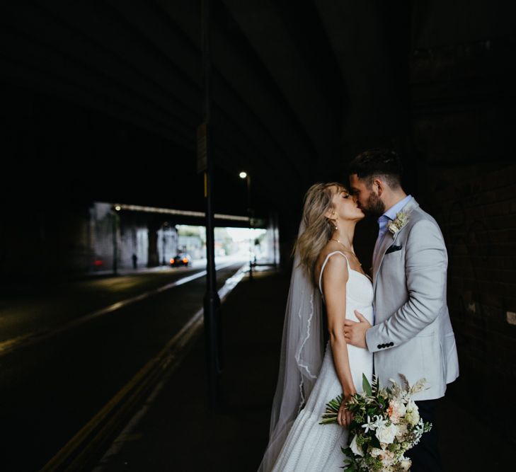 Bride and groom kiss under underpass