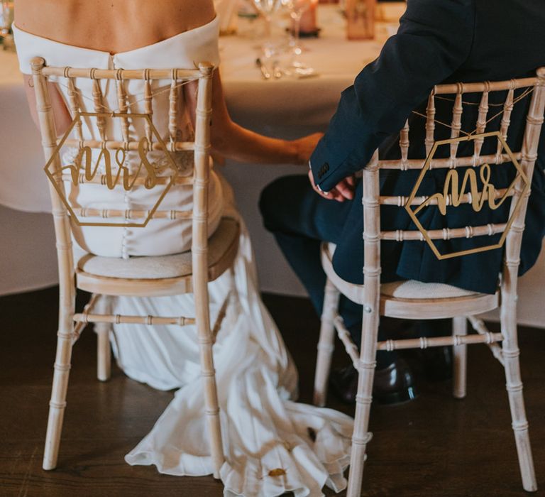 Bride & groom hold hands under the table of wedding reception 