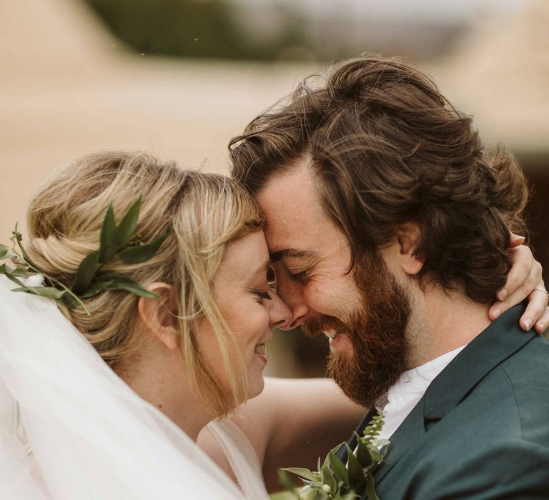 Bride & groom embrace outdoors whilst brides veil blows around them