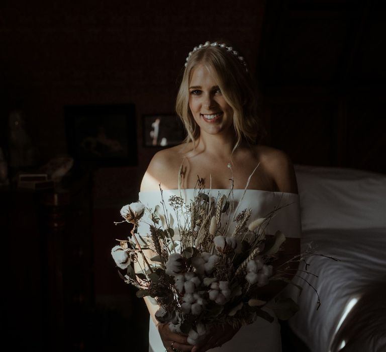 Bride stands with floral bouquet on the morning of her wedding day