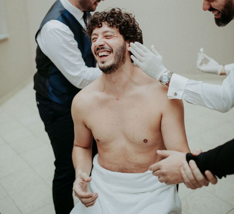 The groom being assisted with getting ready