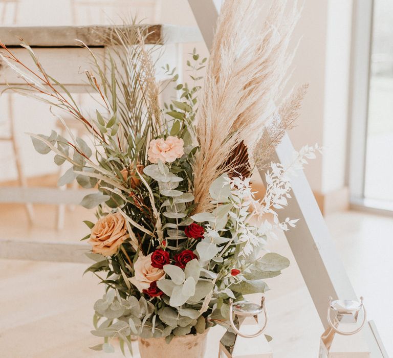 Wedding flower arrangement with eucalyptus, pampas grass, and peach and red roses