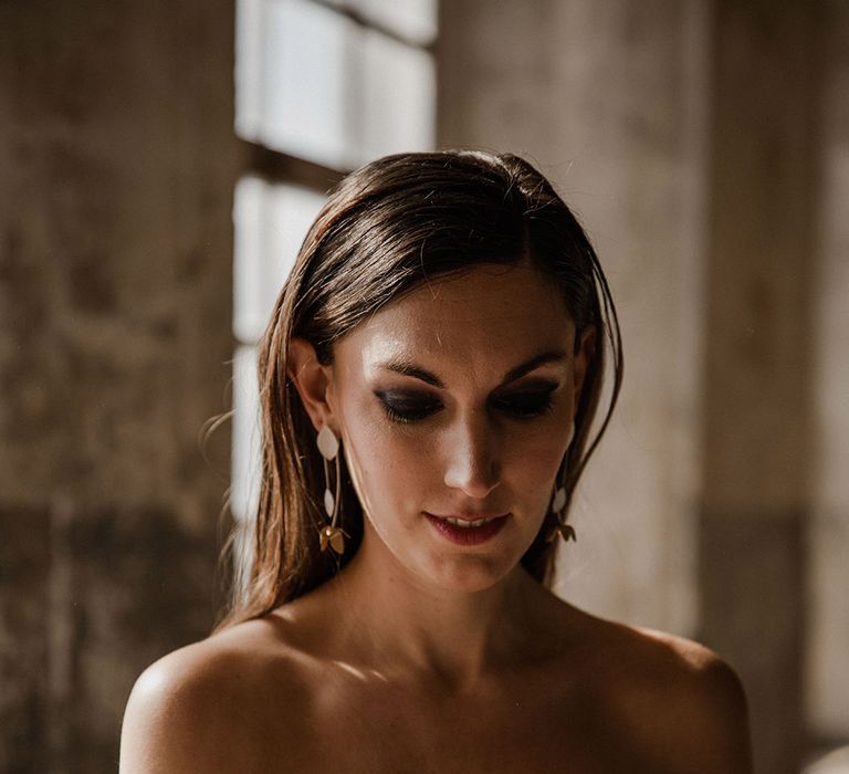 Bride with smokey eye makeup and sleek hair in a strapless crop top. 