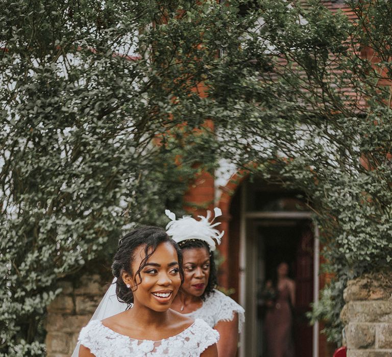 Beautiful bride in a slash neck lace wedding dress holding a red and white bouquet