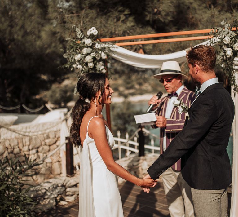 Bride and groom hold hands at outdoor wedding in Croatia