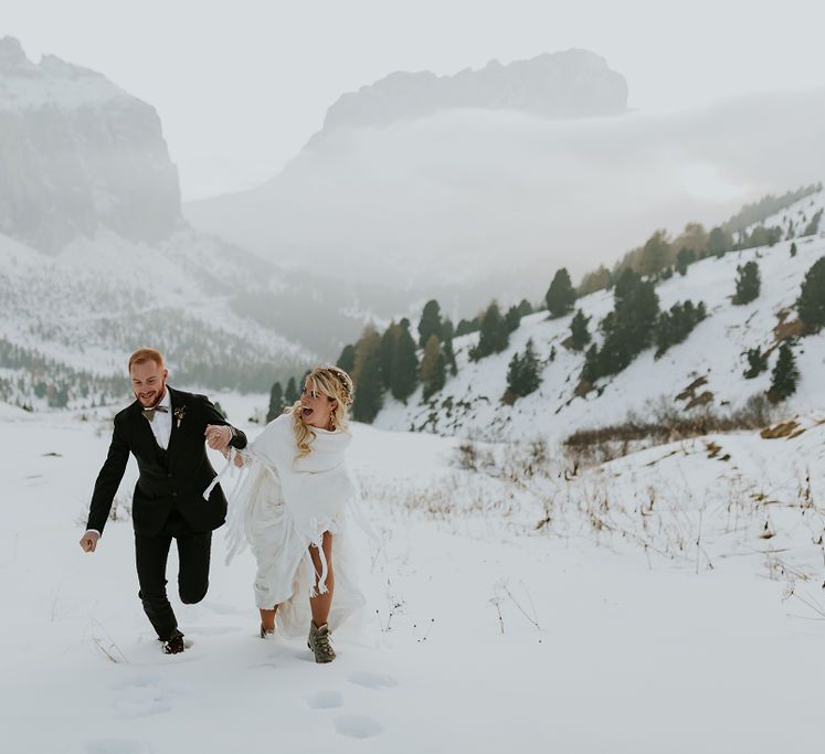 Dolomites wedding elopement with bride and groom running through the snowy mountains 