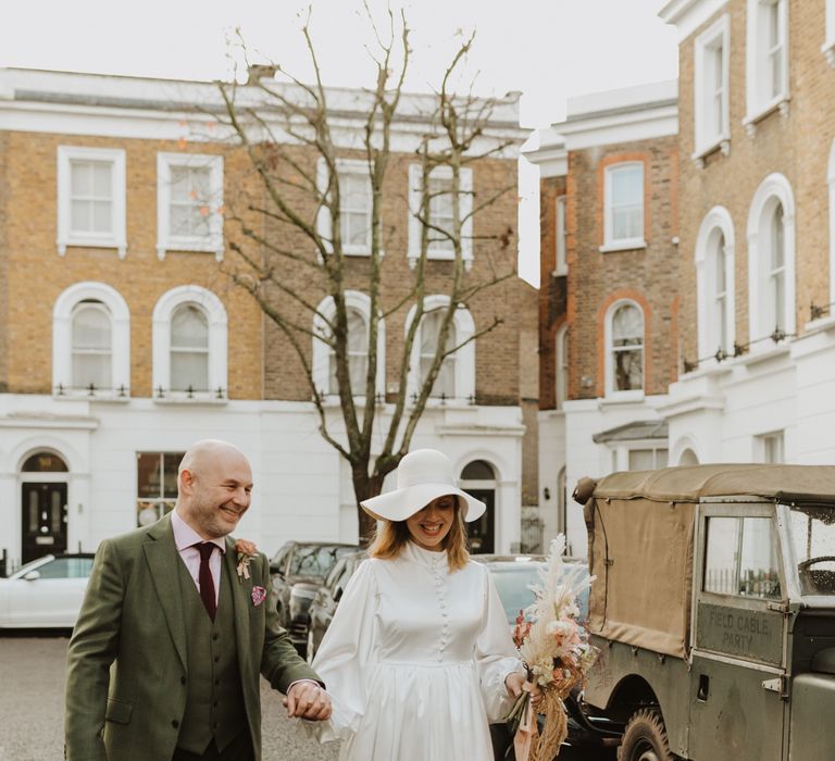 Bride & groom hold hands as they walk together through Chelsea