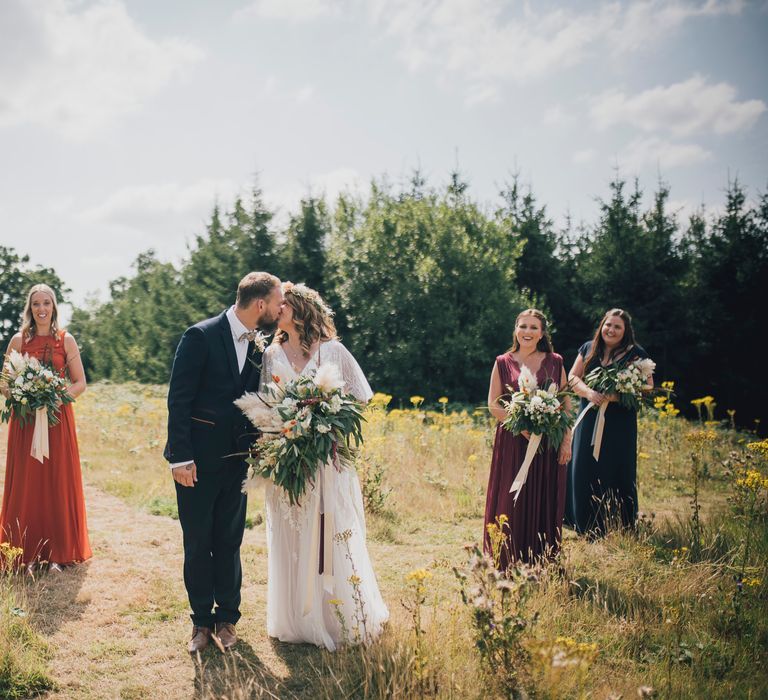 Bride & groom stand in field with their wedding party on their wedding day