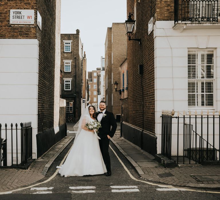 Bride & groom smile and pose with one another in the streets of London