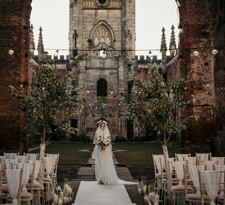 Outdoor wedding ceremony at St Lukes bombed Out Church in Liverpool with festoon lights, trees and pillar candles 