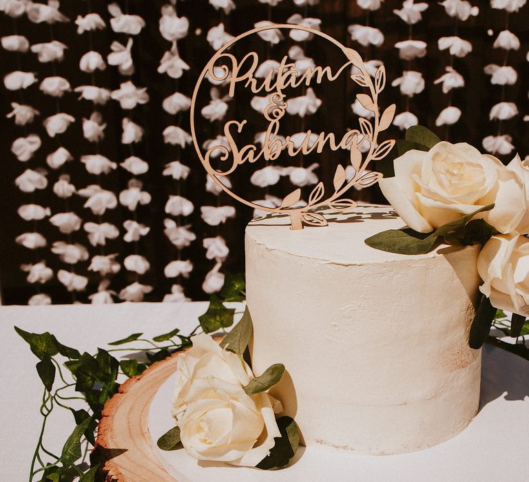 Single tier buttercream wedding cake on a tree slice with lasercut cake topper 