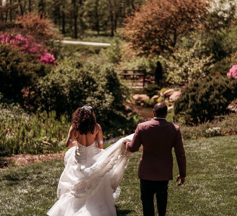 Bride & groom walk through lush green gardens on their wedding day