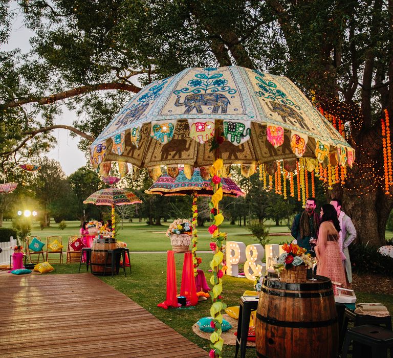 Colourful outdoor reception with vibrant umbrella and personalised letters 