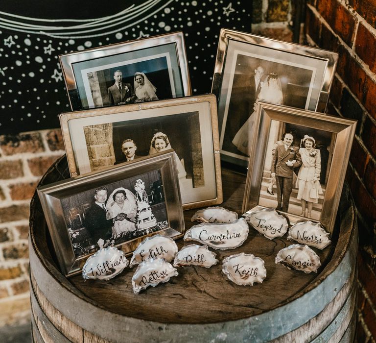 Old family wedding photographs in silver photo frames next to hand painted oysters with names