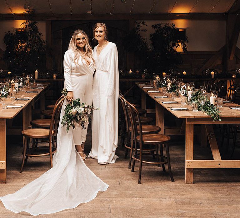 Brides stand in-between wooden tables for rustic reception