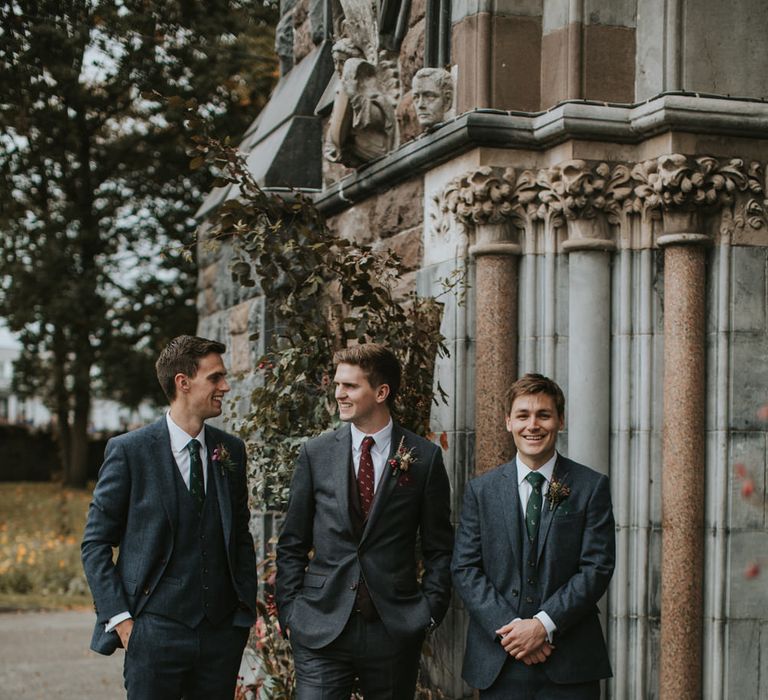 Groom and groomsmen in charcoal grey wedding suits with burgundy and forest green ties for autumnal wedding 