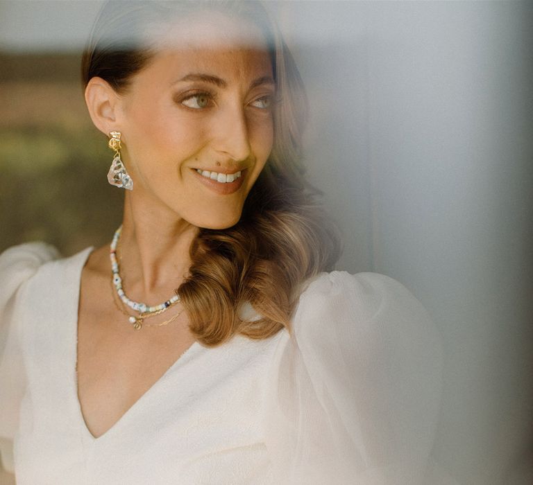 Bride wears her light brown hair to the side in curls with puff sleeved wedding gown 