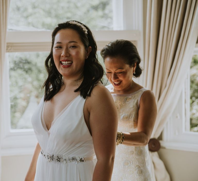 Mother of the bride doing up her daughters wedding dress on the morning of the wedding 