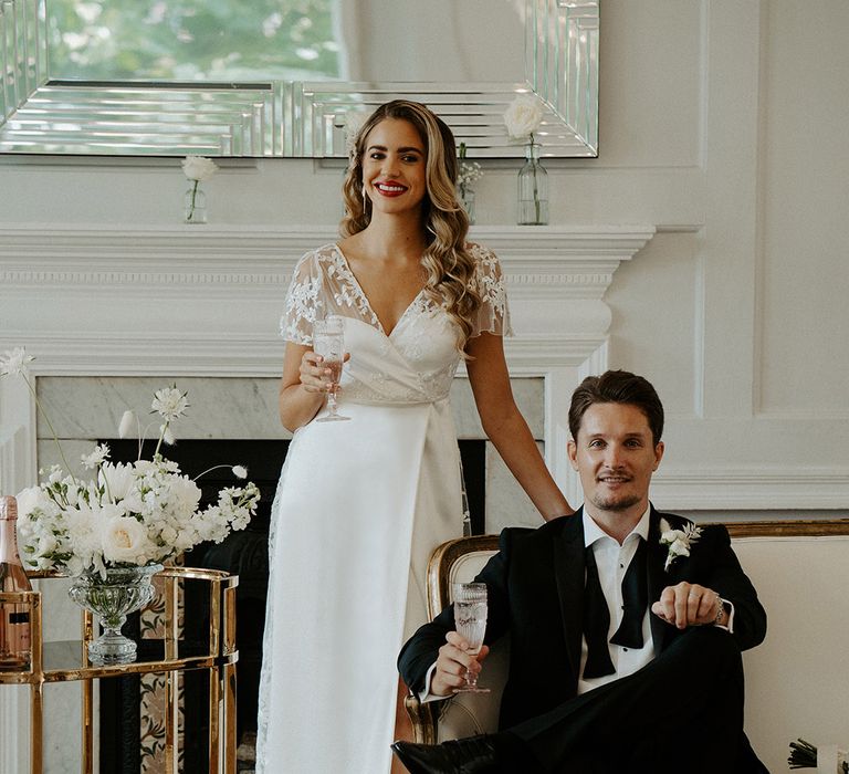 black tie wedding at Winchester Club House with bride and groom sipping champagne next to their gold drinks cart 