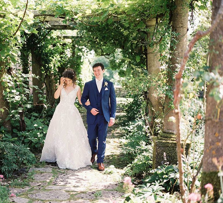 Bride & groom walk through floral archway at Mapperton House