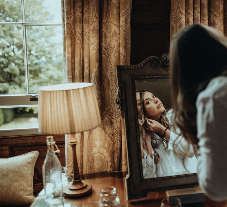 Bride adds her earrings to her wedding day look on the morning of her wedding