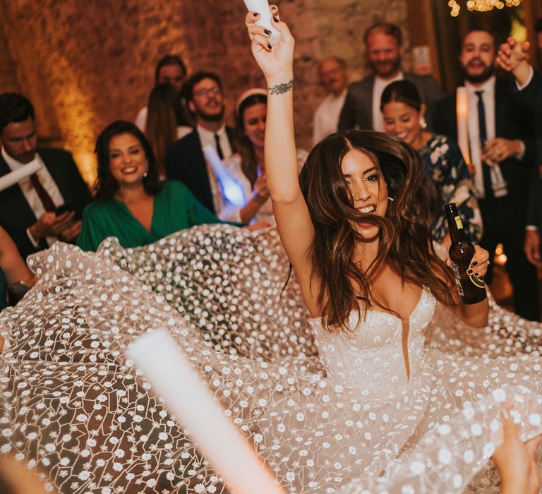 Bride in white applique Pronovias wedding dress and Jimmy Choo wedding shoes spins in centre of circle of wedding guess during evening wedding reception at Notley Abbey wedding