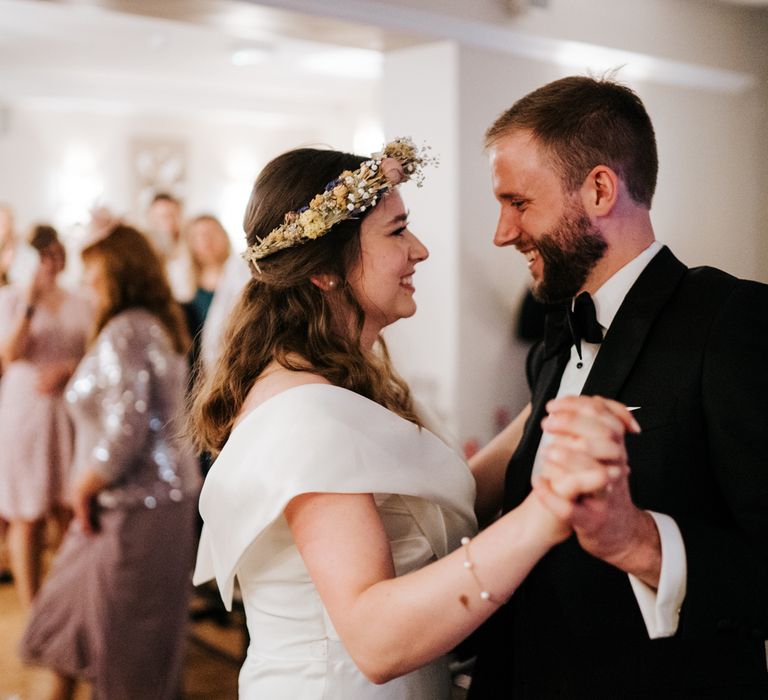 Bride & groom dance during wedding reception as bride wears floral crown