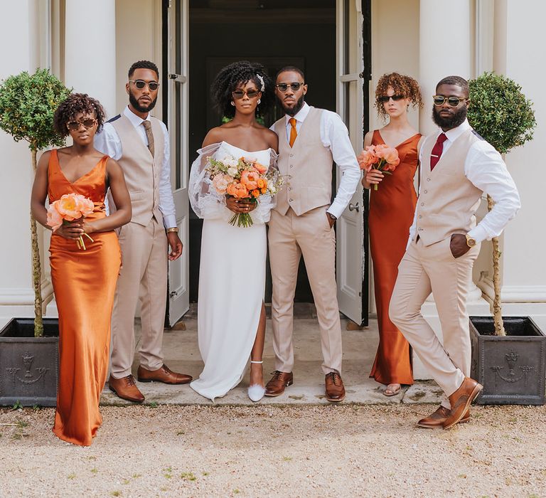 Spring wedding at Modern Hall, London with wedding party in beige suit, satin bridesmaid dresses, strapless wedding dress and sunglasses 