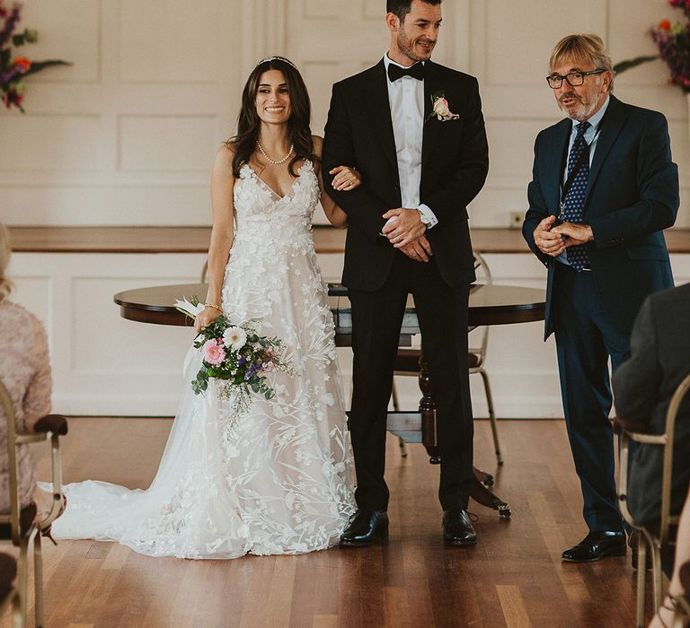 Bride & groom link arms at the front of the room as they leave their ceremony