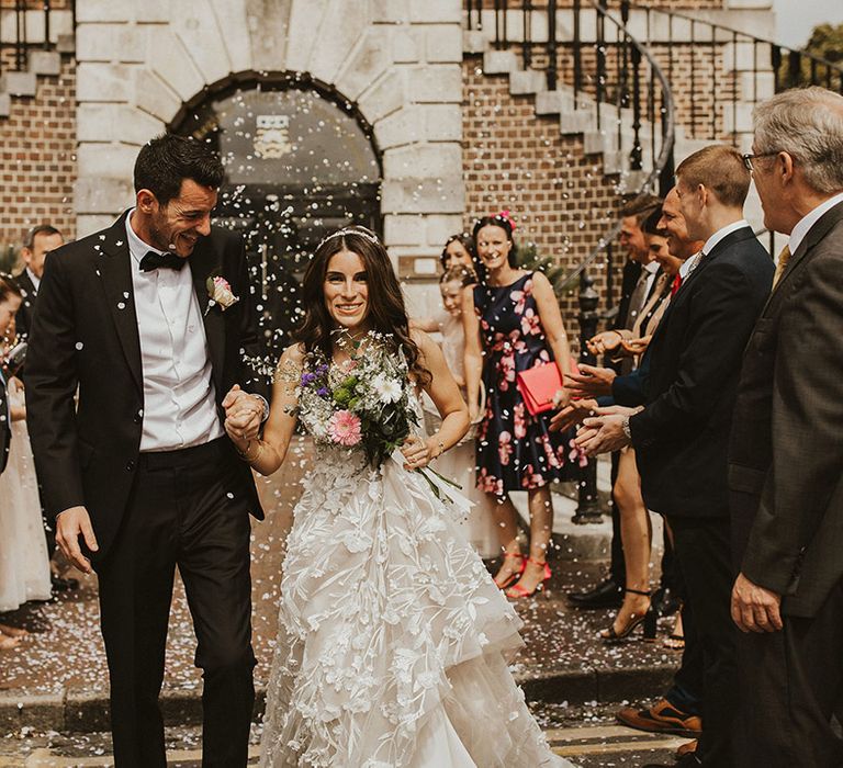 Bride & groom walk through white confetti on their wedding day