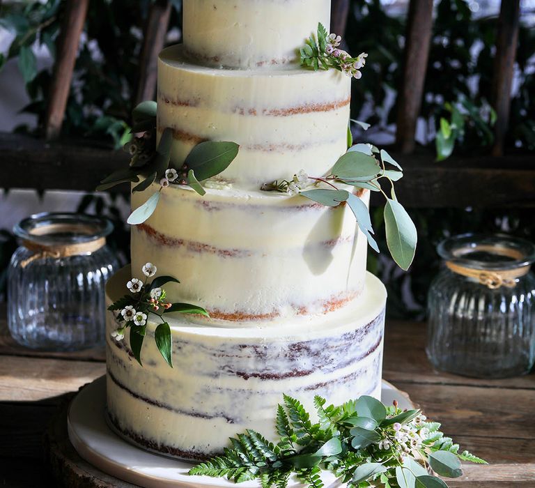 Rustic 4-tier naked wedding cake complete with green foliage