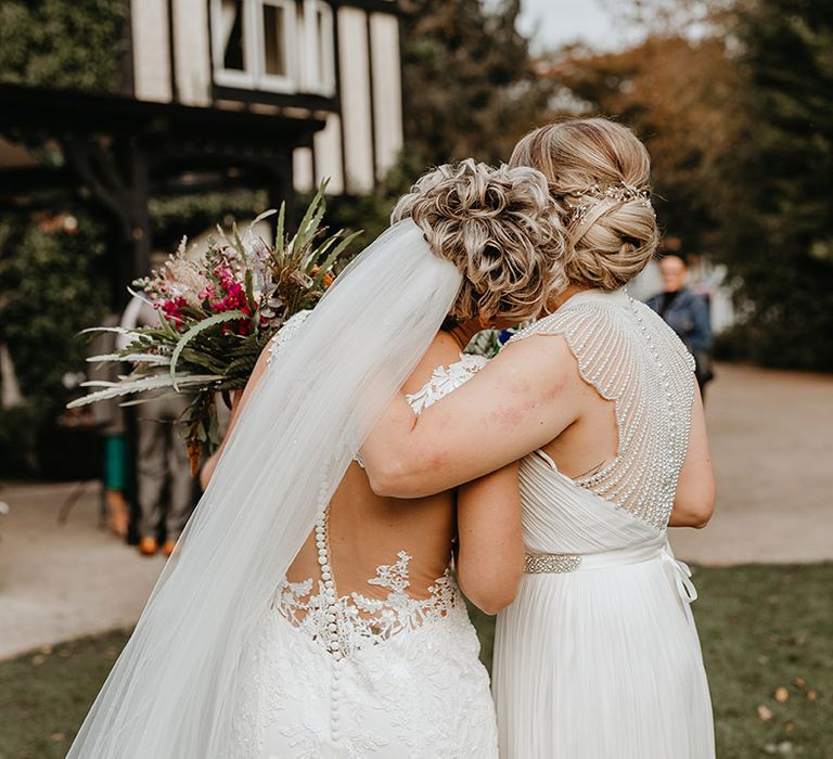 Brides hold their arms around one another after wedding ceremony